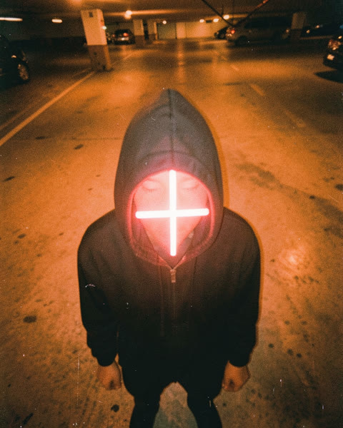 Une capuche avec une croix néon à la place du visage