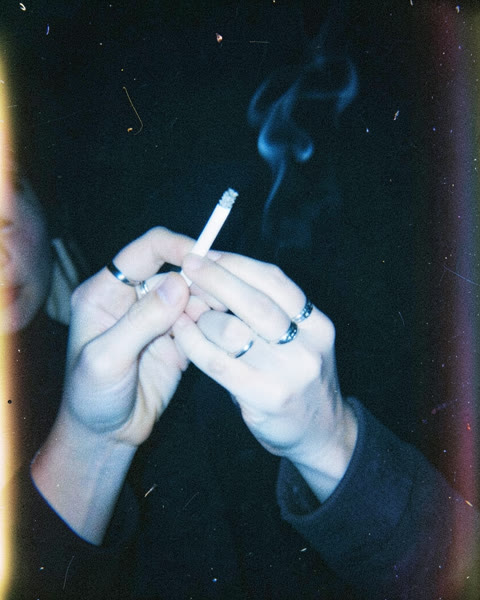 Deux mains avec des bagues et une cigarette